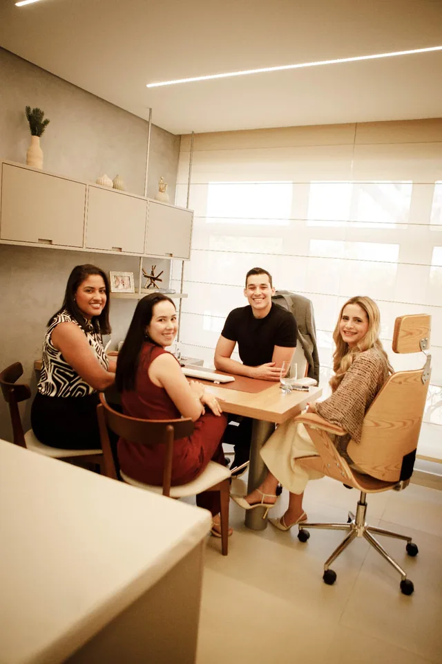 Equipe reunida ao redor da mesa de reunião, conversando e sorrindo